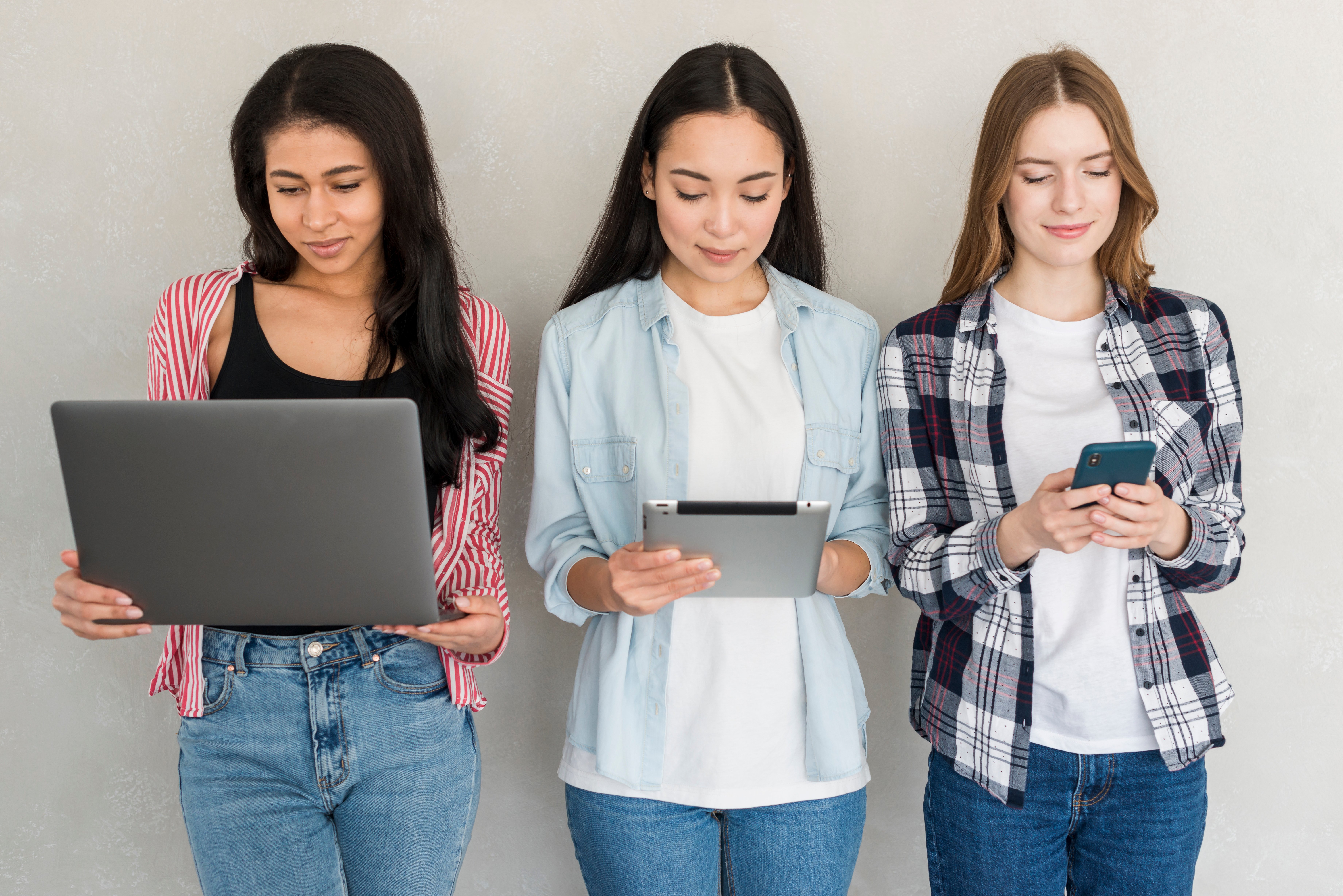 girls-standing-with-gadgets-hands-looking-screens